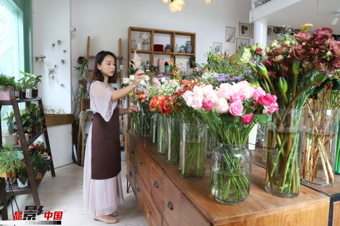 王黎媛是一名河南姑娘，在昆明念完大學(xué)后，就再也舍不下春城的藍(lán)天陽光、青山碧水，更舍不下這里的四時(shí)繁花，于是就干脆留了下來，成了一名媒體人。2017年的時(shí)候又毅然辭去工作，創(chuàng)業(yè)開起了花店，成了都市里的一名“花房姑娘”。圖為王黎媛在自己的花店中整理鮮花。新華網(wǎng) 周亞平/攝 念新洪/文